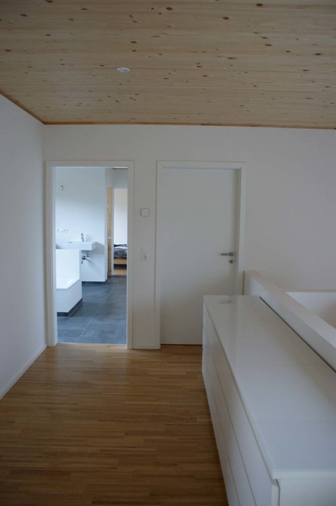 Flur mit Holzboden und Decke, im Hintergrund der Eingang zum Badezimmer