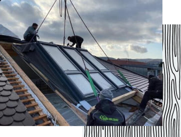Arbeiter der Firma Kuri Holzbau setzen ein Dachfenster ein