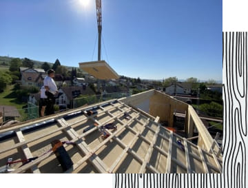 Arbeiter auf einem Dach, bei welchem gerade die Dachkonstruktion entsteht.