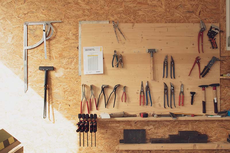 Holzwand an welcher viele unterschiedliche Werkzeuge hängen